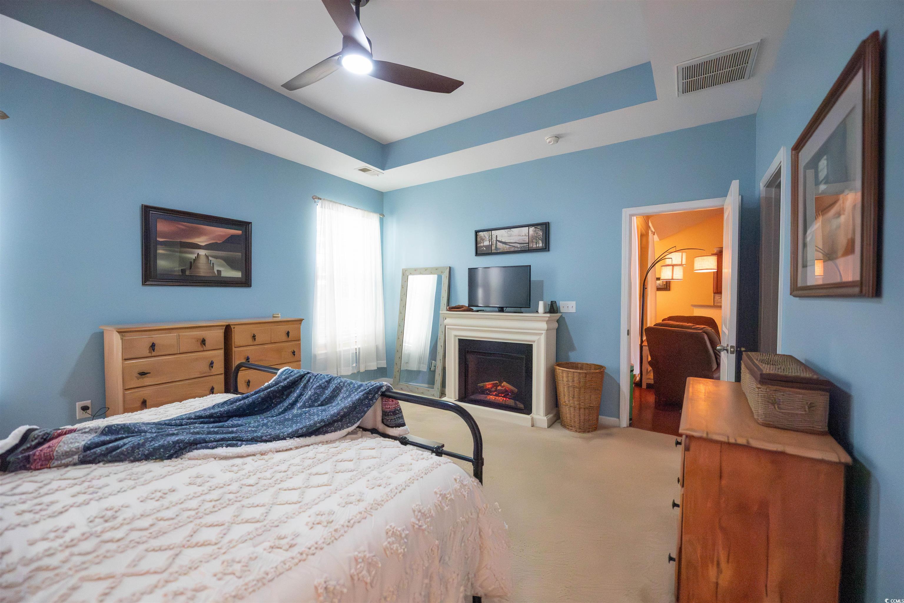 209 Golden Oaks Drive Murrells Inlet, SC 29576 - Photo 27 of 40 Carpeted bedroom with a tray ceiling, a lit fireplace, and a ceiling fan