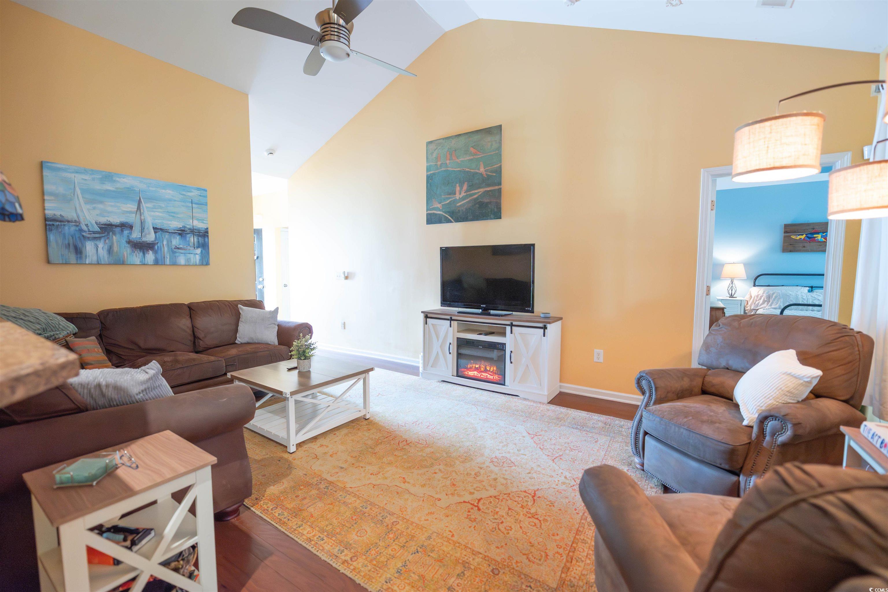 209 Golden Oaks Drive Murrells Inlet, SC 29576 - Photo 28 of 40 Living area featuring wood finished floors, a ceiling fan, high vaulted ceiling, and a warm lit fireplace