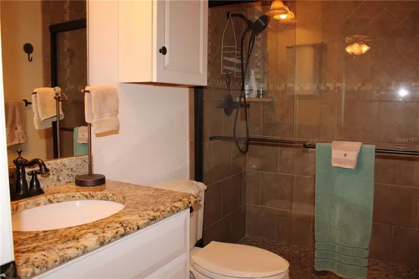 a bathroom with a granite countertop sink toilet and shower