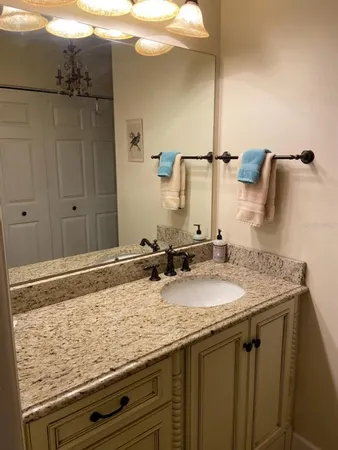 a bathroom with a granite countertop sink and a mirror
