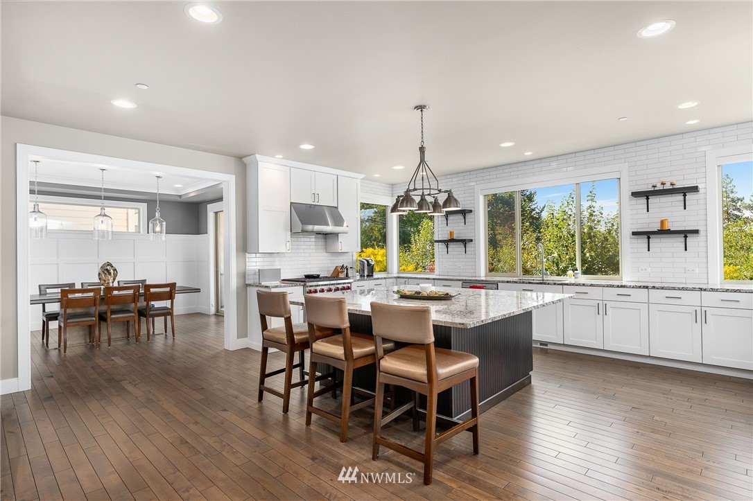 10406 Northeast 52nd Street Kirkland, WA 98033 - Photo 12 of 36 a kitchen with stainless steel appliances granite countertop a stove a refrigerator a kitchen island a dining table and chairs with wooden floor