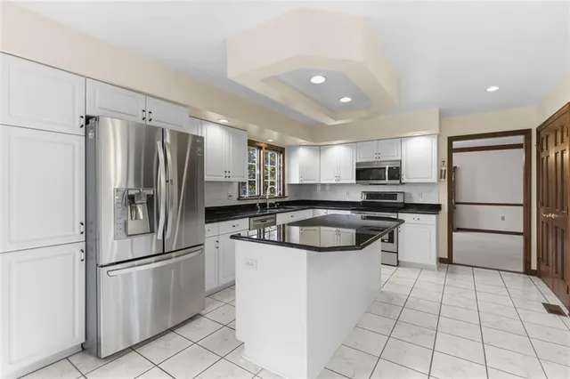 a kitchen with stainless steel appliances granite countertop a refrigerator a sink a stove and white cabinets