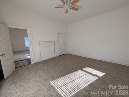 an empty room with a chandelier fan and windows