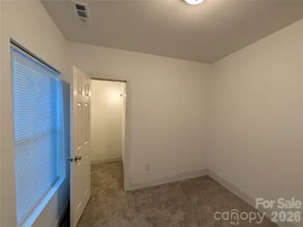 an empty room with a chandelier fan and entryway