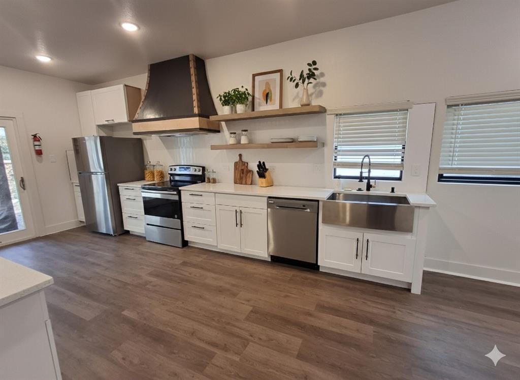 902 Chestnut Street Commerce, TX 75428 - Photo 9 of 18 a kitchen with stainless steel appliances a sink a stove a refrigerator and wooden floor
