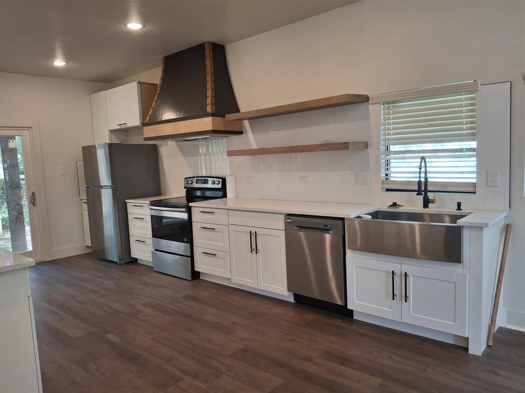 902 Chestnut Street Commerce, TX 75428 - Photo 10 of 18 a kitchen with stainless steel appliances a sink stove and wooden floor