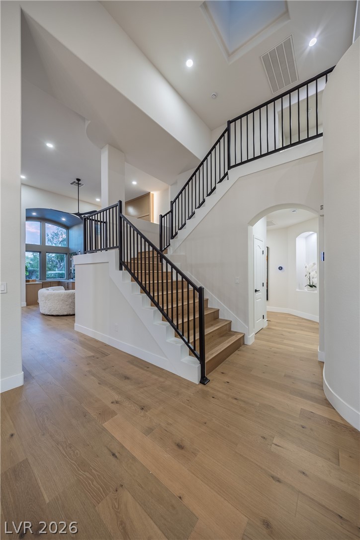 8800 Lusso Las Vegas, NV 89134 - Photo 57 of 85 Stairs with arched walkways, hardwood / wood-style flooring, a high ceiling, and recessed lighting