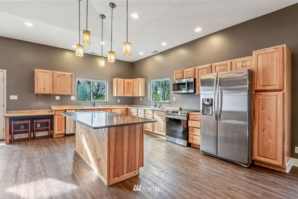 195 Puma Road Longview, WA 98632 - Photo 7 of 39 a kitchen with stainless steel appliances granite countertop a refrigerator a stove top oven a sink dishwasher a dining table and chairs with wooden floor