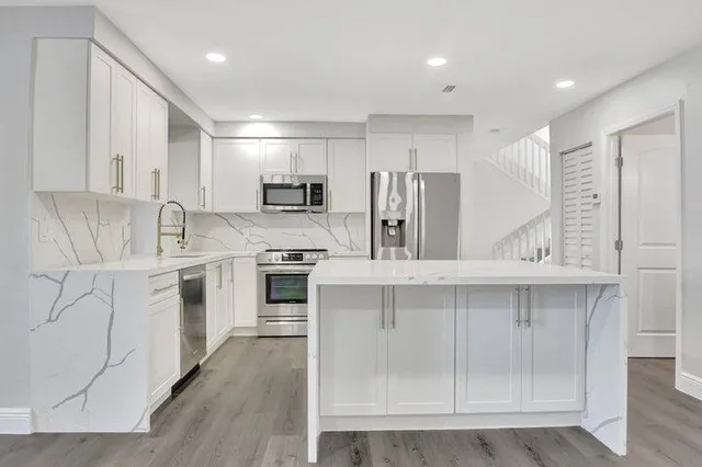 a kitchen with stainless steel appliances a white cabinets and wooden floors