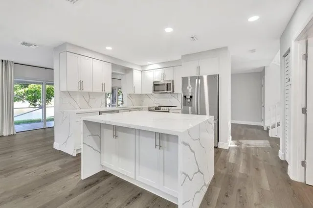 a kitchen with a white cabinets and wooden floor