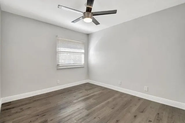 an empty room with a window and a ceiling fan