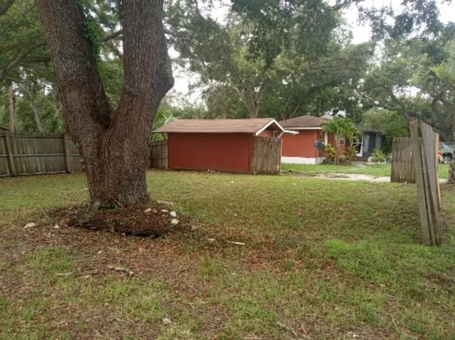 a view of a yard in front of a house with large tree