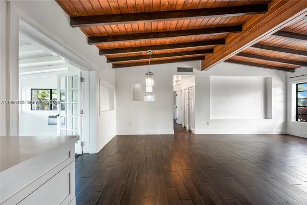 a view of an empty room with wooden floor and a kitchen