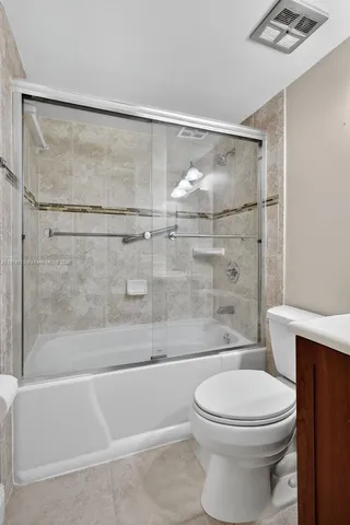 an empty room with a chandelier fan and closet area