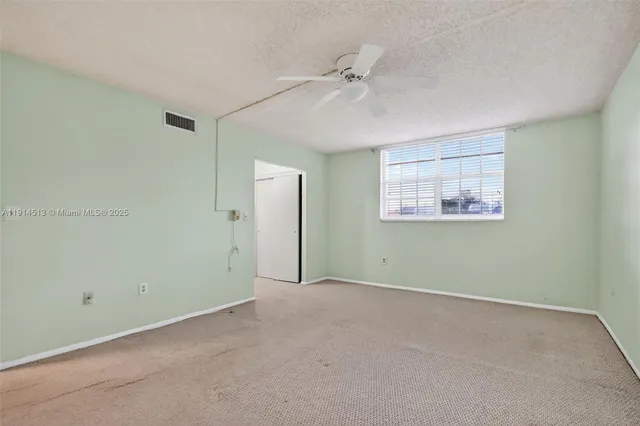an empty room with closet and a ceiling fan
