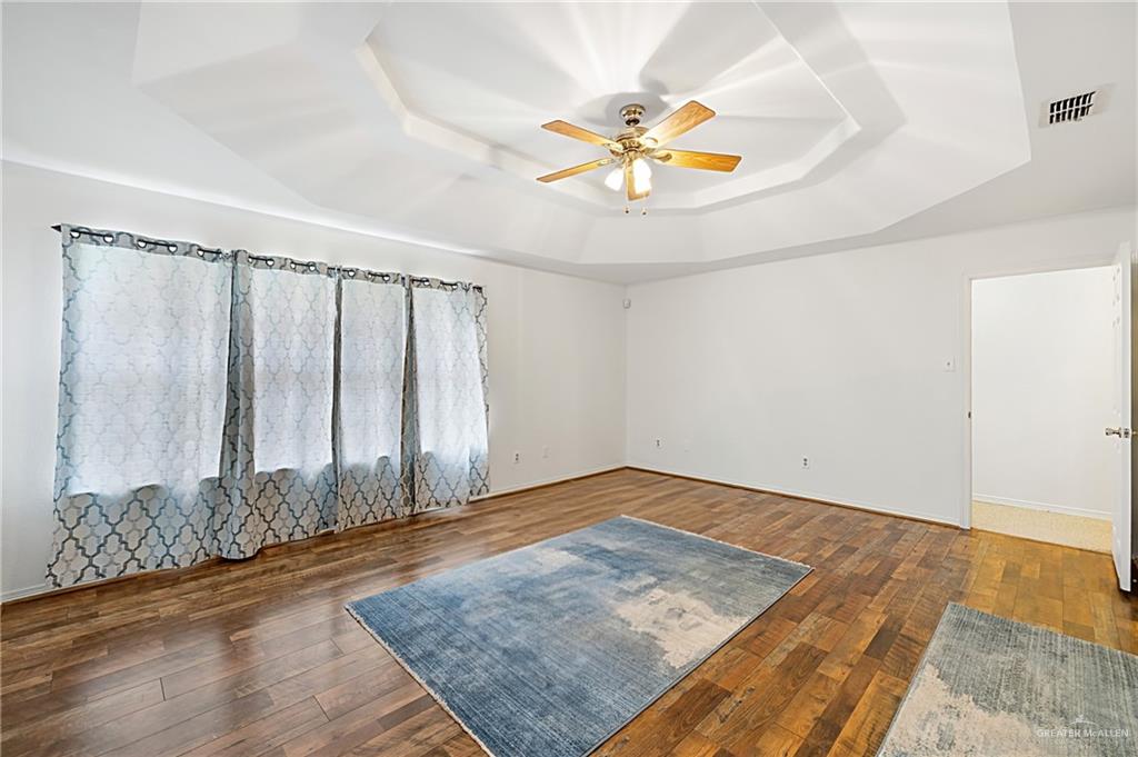 4822 East Canton Road Edinburg, TX 78542 - Photo 4 of 28 an empty room with wooden floor chandelier fan and windows