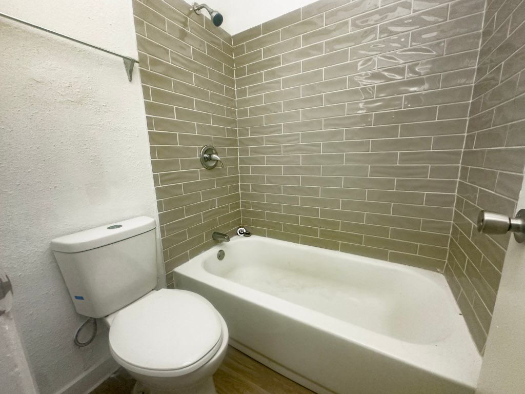 4500 Witham Lane, Unit 101 Austin, TX 78745 - Photo 5 of 27 Bathroom featuring tub / shower combination, a textured wall, and wood finished floors