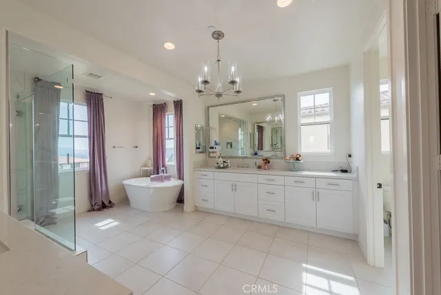 a bathroom with a tub a window and a glass door shower