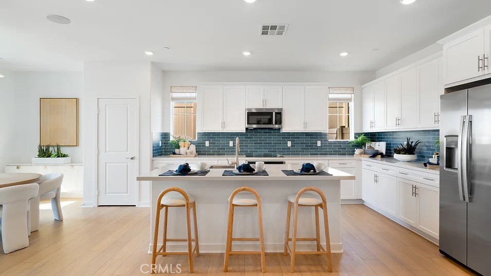 a kitchen with stainless steel appliances granite countertop a stove a sink a refrigerator a dining table and chairs