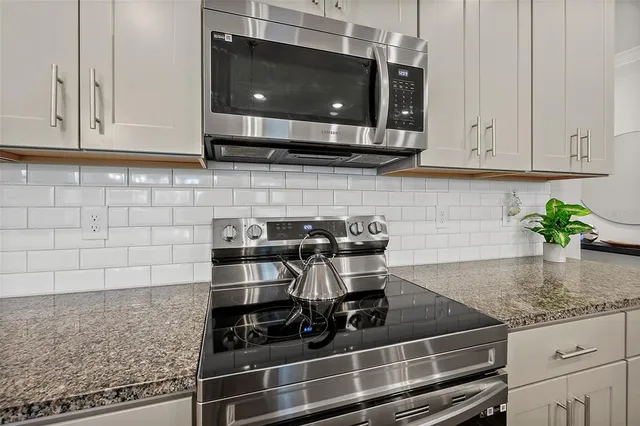 a kitchen with granite countertop a sink a stove and cabinets