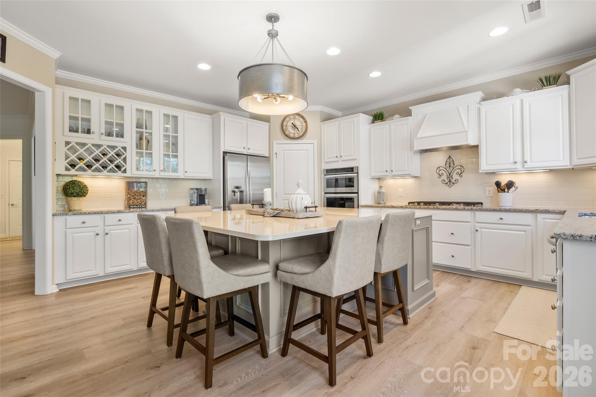 1002 Falling Leaf Street Indian Land, SC 29707 - Photo 10 of 45 a kitchen with stainless steel appliances kitchen island granite countertop a sink a stove a dining table and chairs with wooden floor