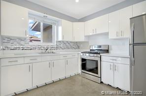 5391 West 9th Lane Hialeah, FL 33012 - Photo 2 of 22 a kitchen with granite countertop white cabinets and white appliances