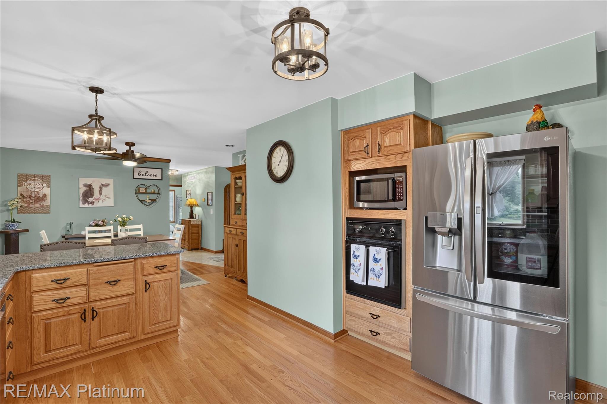 4457 Bradley Road Gregory, MI 48137 - Photo 16 of 79 Open-concept kitchen featuring wood-finish flooring, built-in stainless steel appliances, granite-style countertops, and natural wood cabinetry