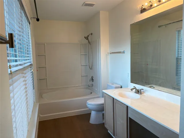 a bathroom with a granite countertop sink a toilet and shower