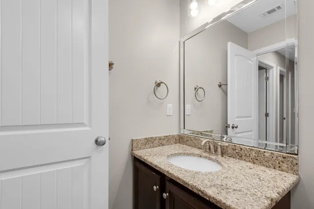 a bathroom with a granite countertop sink and a mirror