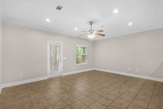 an empty room with chandelier fan and windows