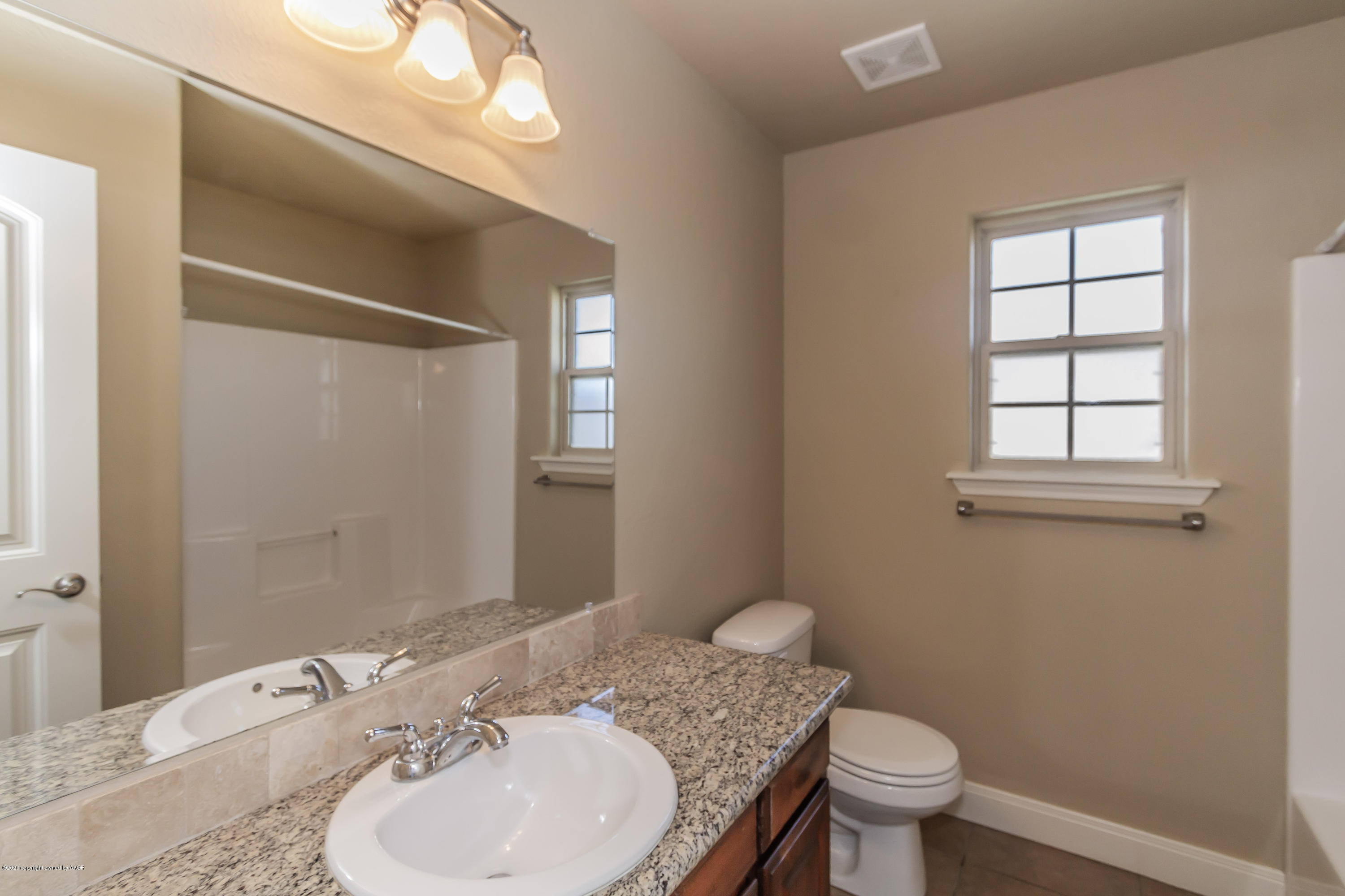 3813 Arden Road Amarillo, TX 79118 - Photo 24 of 33 a bathroom with a granite countertop sink toilet a mirror and shower