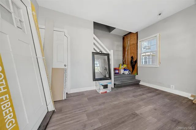 a view of a hallway to a livingroom with wooden floor and window