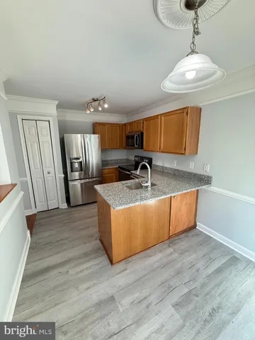 a kitchen with stainless steel appliances granite countertop a sink a refrigerator and wooden floor