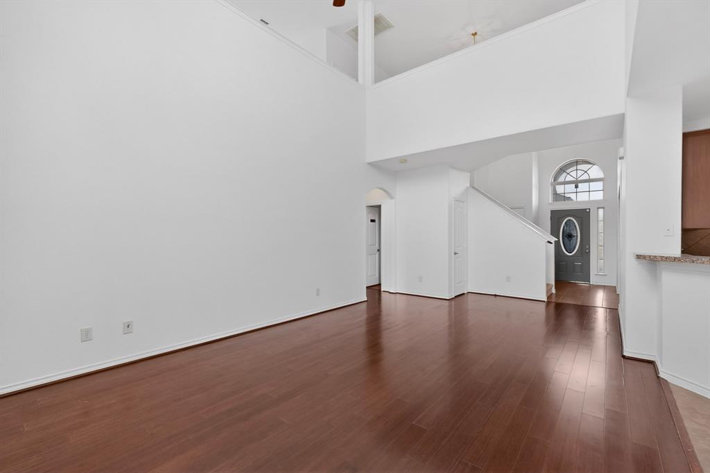 426 Harding Lane Lavon, TX 75166 - Photo 8 of 40 Expansive living area with wood-finish flooring, high ceilings, white painted walls, and a prominent staircase
