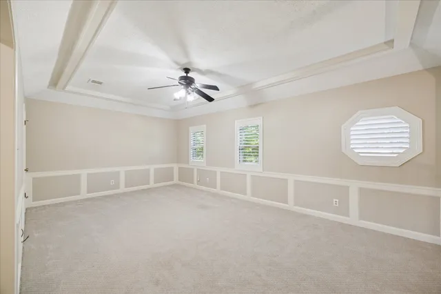 an empty room with windows and fan