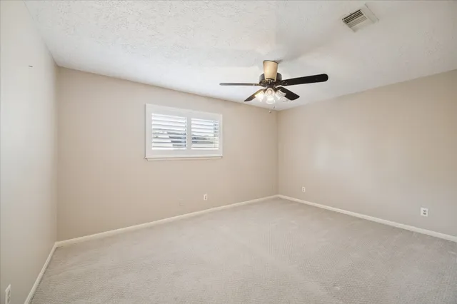 an empty room with a window and a ceiling fan