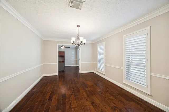 an empty room with wooden floor and chandelier