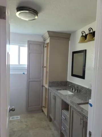 a bathroom with a granite countertop sink and a mirror