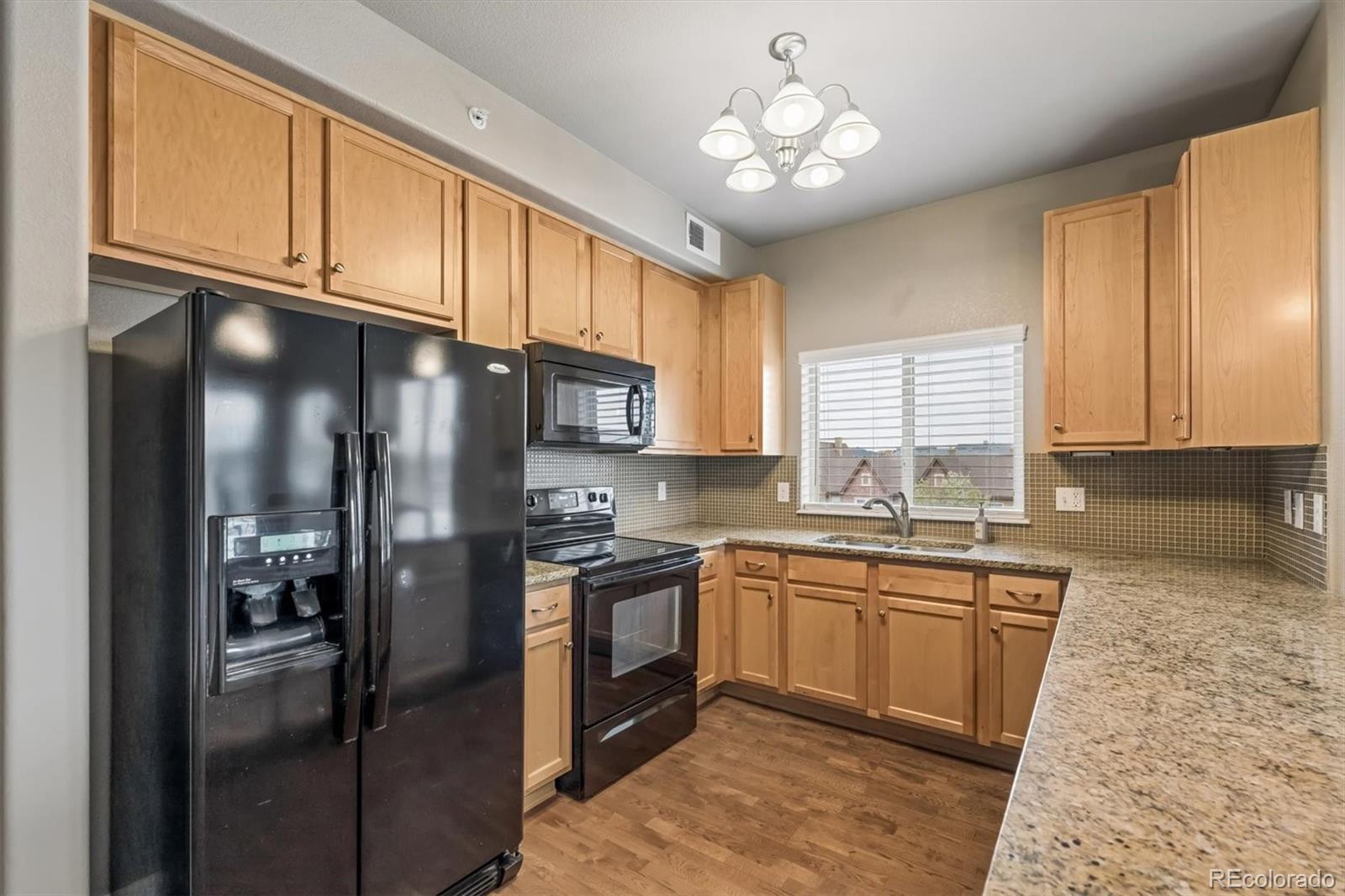 1044 Rockhurst Drive, Unit 404 Highlands Ranch, CO 80129 - Photo 13 of 28 a kitchen with stainless steel appliances granite countertop a refrigerator a sink dishwasher a stove with wooden cabinets and floor
