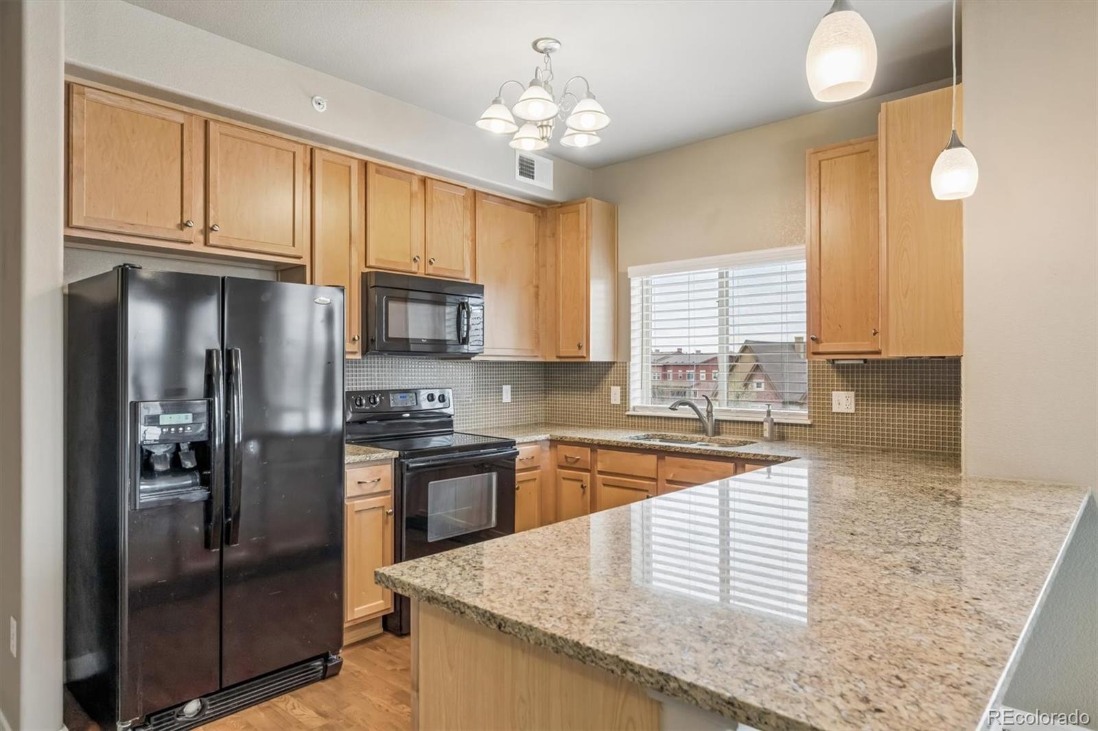 1044 Rockhurst Drive, Unit 404 Highlands Ranch, CO 80129 - Photo 10 of 28 a kitchen with stainless steel appliances granite countertop a refrigerator a sink dishwasher a stove and a dining table with wooden floor