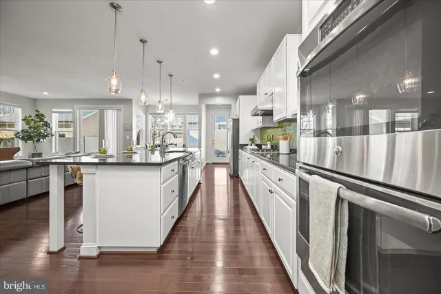 a view of a kitchen with kitchen island wooden floor center island and stainless steel appliances