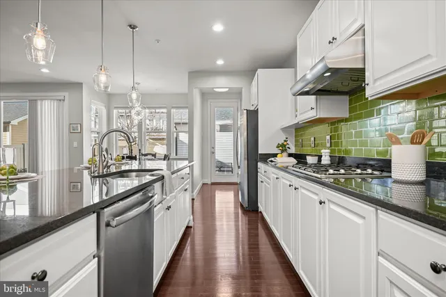 a large kitchen with stainless steel appliances granite countertop a stove and a large window