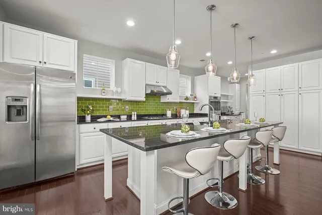 a kitchen with stainless steel appliances granite countertop a sink a stove a refrigerator cabinets and dining table