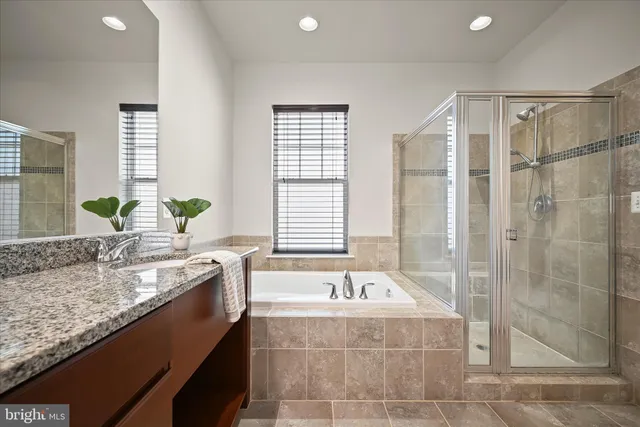 a bathroom with a granite countertop bathtub a sink and a shower