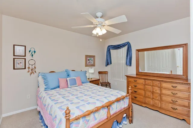 a bedroom with a bed a dresser and a chandelier