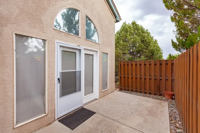 a view of a white house with a small yard and potted plants