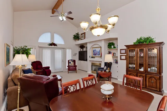 a living room with couches a chandelier and a dining table with wooden floor