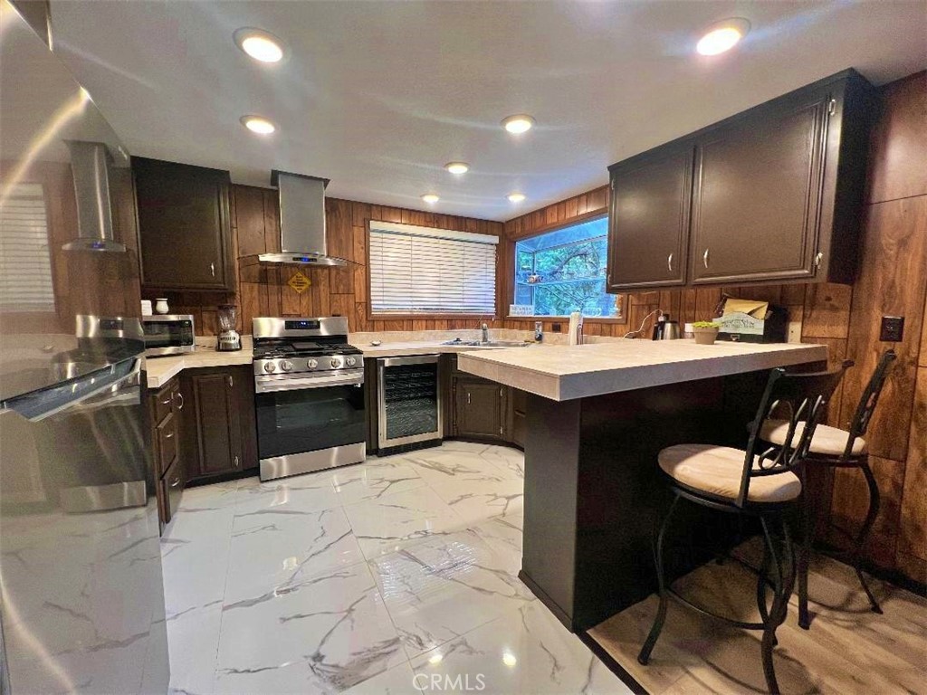 1198 Arbula Drive Crestline, CA 92325 - Photo 7 of 27 a kitchen with stainless steel appliances kitchen island granite countertop a sink a stove a refrigerator and chairs