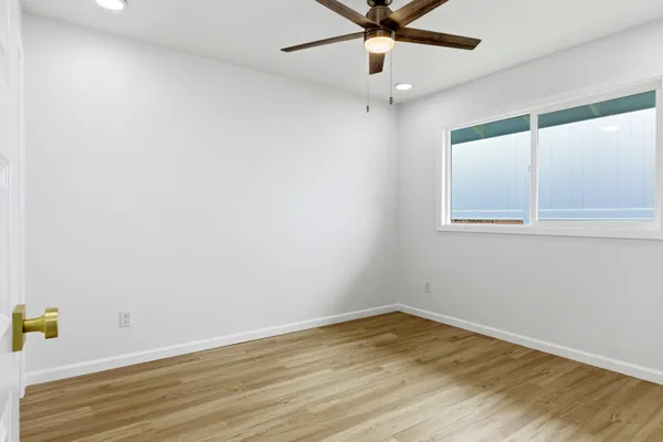 an empty room with a window and ceiling fan