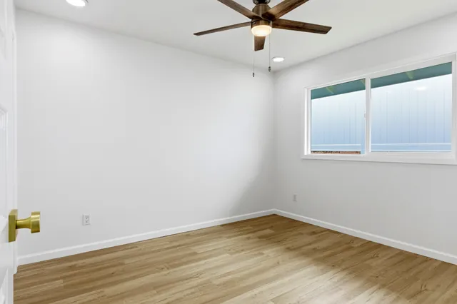 an empty room with a window and ceiling fan